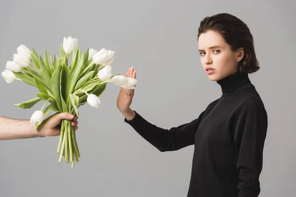 Vista cortada do homem segurando tulipas brancas perto da mulher chateada gesticulando isolado no cinza — Fotografia de Stock