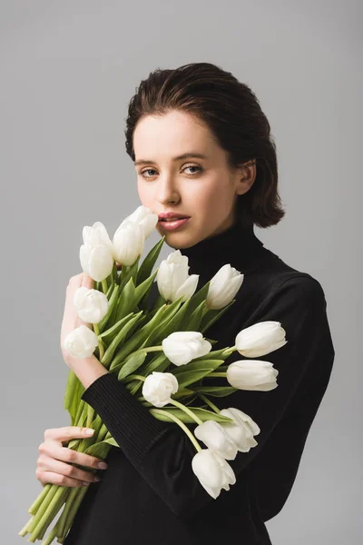 Mulher morena atraente segurando tulipas brancas isoladas em cinza — Fotografia de Stock