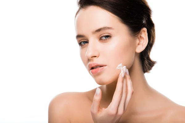 Young brunette woman applying face cream isolated on white — Stock Photo