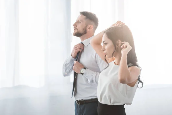 Attractive woman touching hair near bearded man in suit — Stock Photo