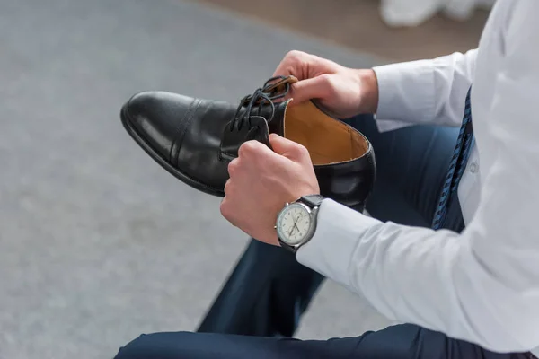 Cropped view of man holding black shoe in hands — Stock Photo