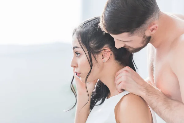 Musculoso barbudo hombre tocando morena mujer hablando en smartphone - foto de stock