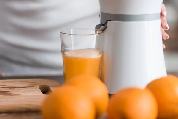 Cropped view of woman near juicer and glass of orange juice — Stock Photo