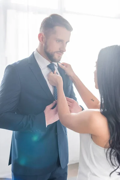 Брюнетка жінка торкається краватки красивого бородатого чоловіка в костюмі — стокове фото