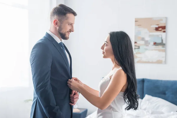 Cheerful brunette girl touching formal wear of handsome man — Stock Photo