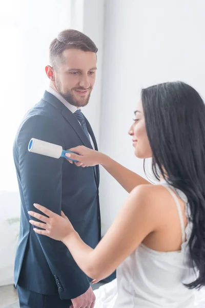 Attractive brunette girl cleaning formal wear of handsome bearded man — Stock Photo