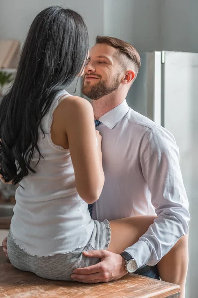 Vista trasera de la mujer sentada en la mesa cerca de novio guapo en traje - foto de stock