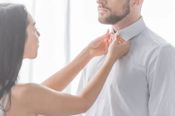 Brunette woman touching collars of bearded man in white shirt — Stock Photo