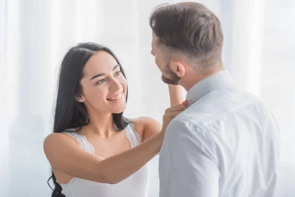 Cheerful woman touching collars of bearded boyfriend in white shirt — Stock Photo