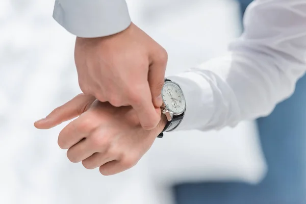 Cropped view of man in white shirt touching watch on hand — Stock Photo