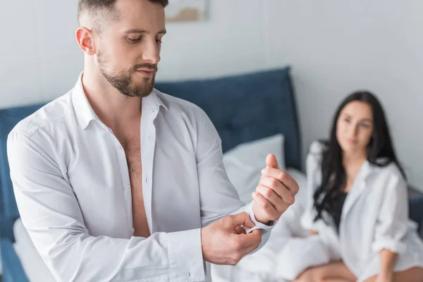 Selektiver Fokus eines gutaussehenden Mannes in weißem Hemd in der Nähe einer Frau auf dem Bett — Stockfoto