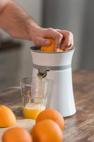 Cropped view of man preparing orange juice in kitchen — Stock Photo