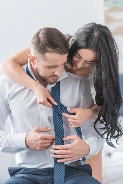 Brunette woman tying tie of handsome bearded boyfriend — Stock Photo