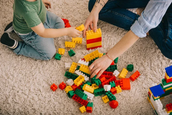 Vista cortada de mãe e filho brincando com blocos de brinquedo no tapete — Fotografia de Stock