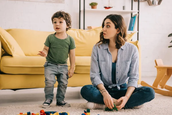 Mother and son playing with toy blocks on carpet — Stock Photo