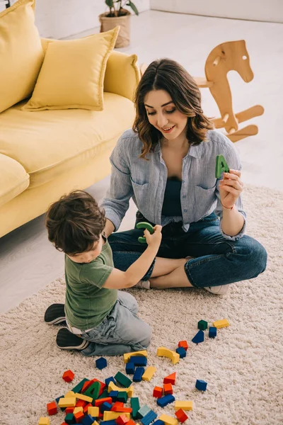 Mãe e filho brincando com blocos de brinquedo no tapete — Fotografia de Stock
