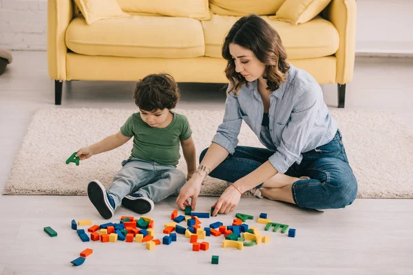 Mutter und Sohn spielen mit Spielzeugklötzen auf Teppich — Stockfoto