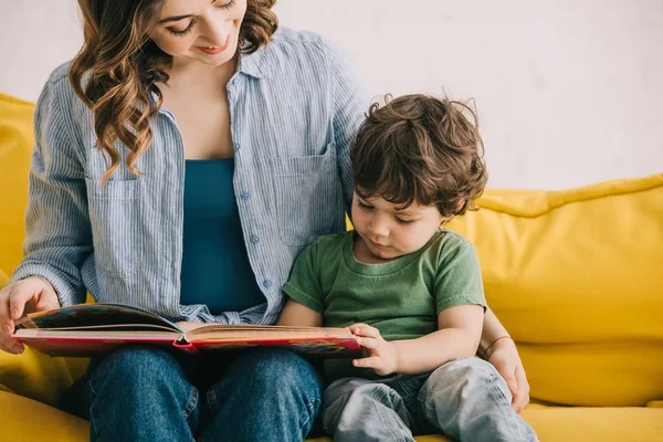 Cropped view of mother and son reading book together — Stock Photo
