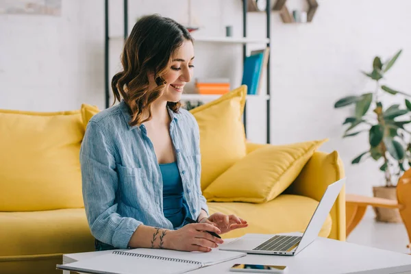 Freelancer sonriente en camisa azul trabajando con laptop en salón - foto de stock