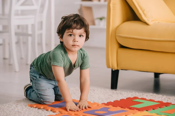 Niedliches Kind im grünen T-Shirt spielt mit Puzzle-Matte — Stockfoto