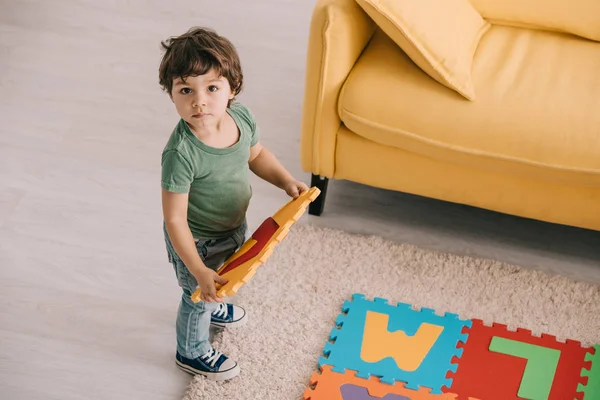 Overhead view of cute child in green t-shirt playing with puzzle mat — Stock Photo