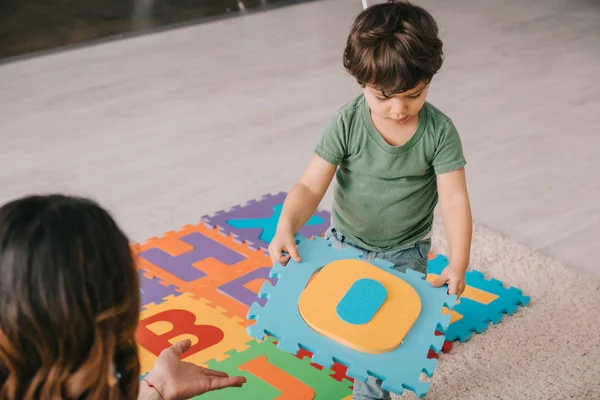 Visão cortada de mãe e filho aprendendo alfabeto com tapete de quebra-cabeça — Fotografia de Stock