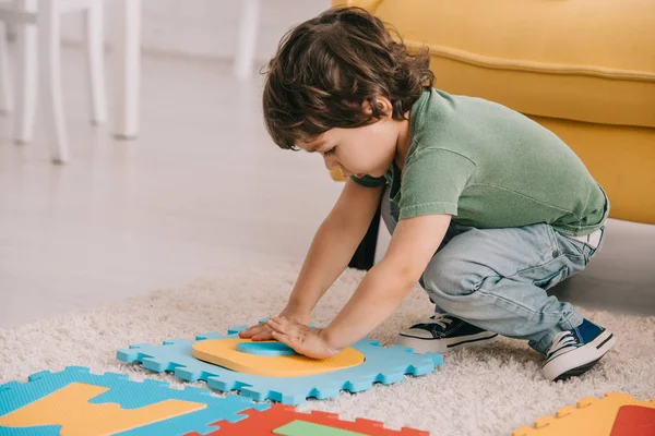 Bonito criança no verde t-shirt jogar com puzzle mat — Fotografia de Stock