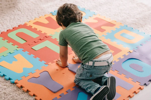 Cute child in green t-shirt playing with puzzle mat — Stock Photo
