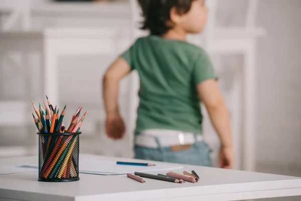 Selective focus of child near table with color pencils — Stock Photo