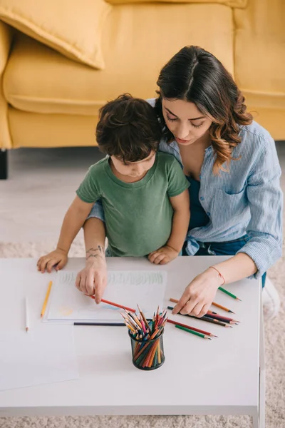 Mutter und Sohn zeichnen mit Buntstiften im Wohnzimmer — Stockfoto