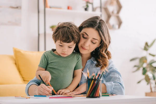 Mutter und Sohn zeichnen mit Buntstiften im Wohnzimmer — Stockfoto