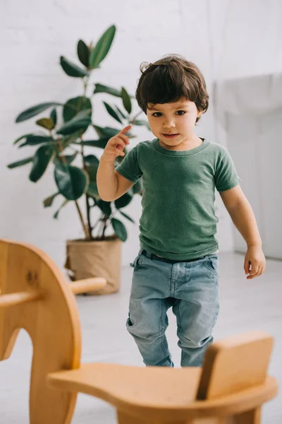 Bambino in t-shirt verde e cavallo a dondolo in legno — Foto stock