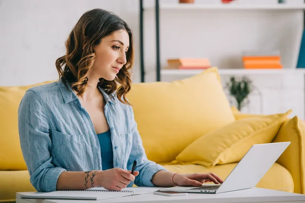 Ocupada mulher atraente trabalhando com laptop na sala de estar — Fotografia de Stock