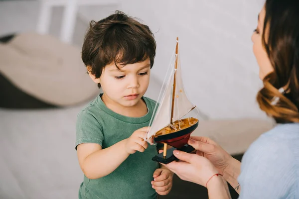 Обрезанный вид матери и маленького сына с игрушечным кораблем — стоковое фото