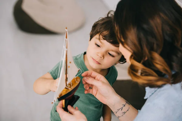 Vista recortada de la madre y el pequeño hijo con barco de juguete - foto de stock