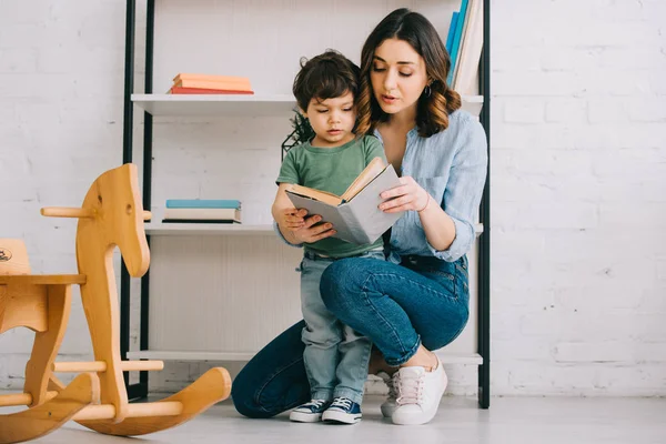 Libro de lectura de madre e hijo en la sala de estar - foto de stock