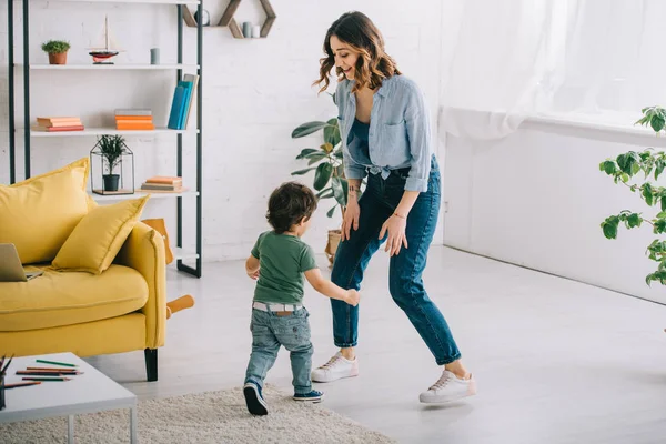 Vue pleine longueur de la femme souriante avec son fils dans le salon — Photo de stock