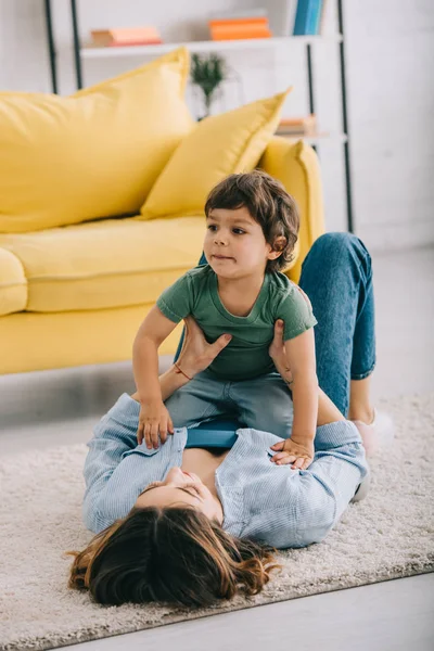 Feliz mãe e filho brincando no tapete na sala de estar — Fotografia de Stock