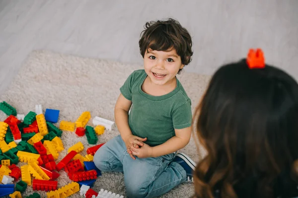 Madre e hijo jugando con lego en alfombra en la sala de estar - foto de stock