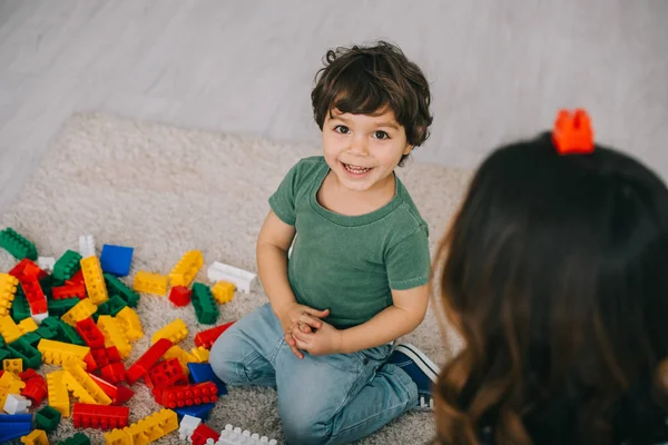 Mother and son playing with lego on carpet in living room — Stock Photo