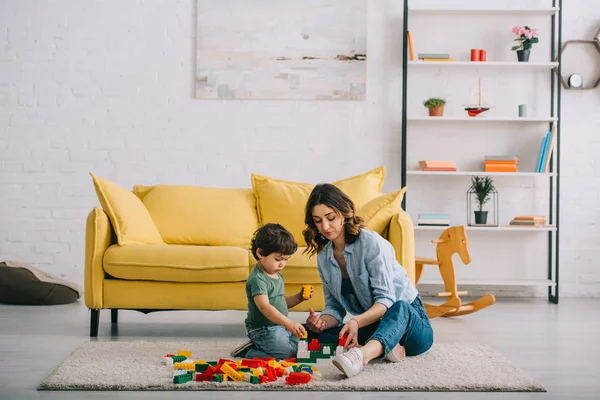 Mother and son playing with lego on carpet in living room — Stock Photo