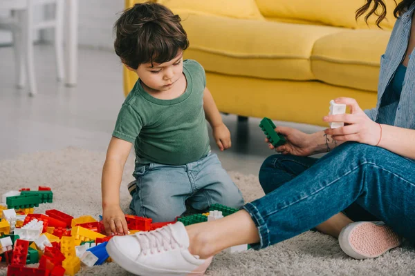 Vista cortada de mãe e filho brincando com lego no tapete na sala de estar — Fotografia de Stock