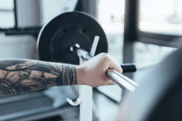 Corte vista de homem tatuado exercitando com barbell no centro de esportes — Fotografia de Stock