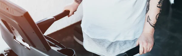 Plano panorámico del hombre tatuado con sobrepeso corriendo en la cinta de correr en el centro deportivo - foto de stock