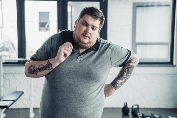 Overweight tattooed man holding towel at sports center — Stock Photo