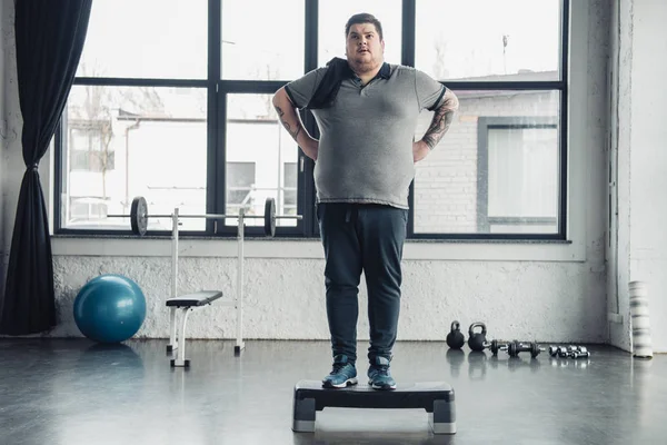 Overweight man with towel standing on step platform at sports center — Stock Photo