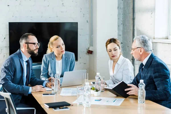 Handsome businessmen in eye glasses sitting near attractive businesswomen — Stock Photo