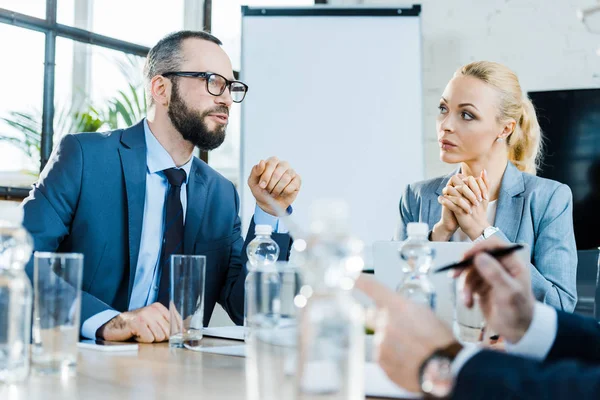 Selektiver Fokus eines bärtigen Geschäftsmannes, der in der Nähe von Kollegen im Konferenzraum spricht — Stockfoto