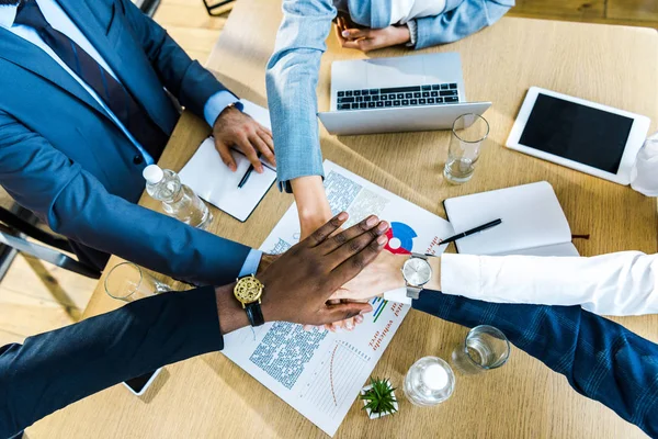 Top view of multicultural businessmen and businesswomen putting hands together — Stock Photo