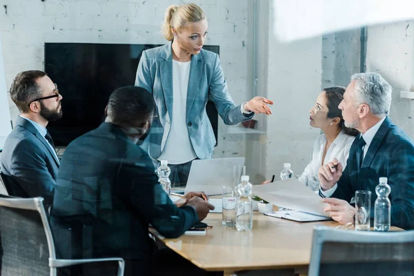 Selektiver Fokus des Business Coaches beim Reden und Gesten im Konferenzraum in der Nähe multikultureller Mitarbeiter — Stockfoto